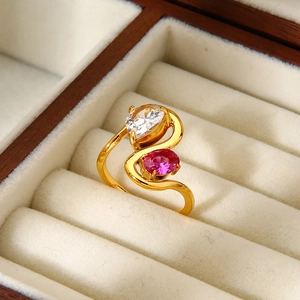 Detalle de anillo dorado ondulado con piedra pera blanca y circón óvalo rosa