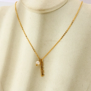 Detail of 18k gold plated mama letter pendant with a small white pearl on a fine chain