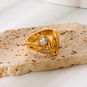 Close-up of gold pear-cut zircon ring with V-shaped diamond accents on travertine stone