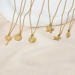 Flat lay of six gold ocean necklaces featuring starfish, seashell, and palm tree charms
