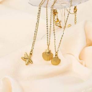 Detail of gold starfish and seashell pendants on elegant stainless steel cross chains