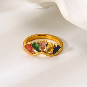 Gros plan d'une bague en acier doré ornée de cinq pierres de zircon colorées taille poire
