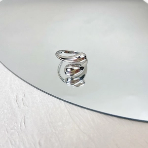 Gepolijste zilveren druppelring met reflectie op een ronde spiegel en stenen ondergrond