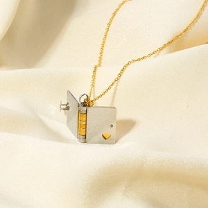 Close-up of a Y2K style openable book pendant necklace on soft beige silk