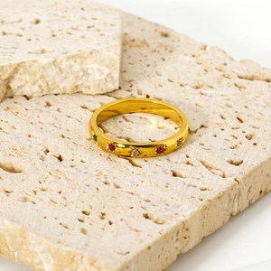 Detail of gold star-set ring with colorful red and green zircon on travertine stone