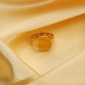 Macro detail van 18k vergulde roestvrijstalen ring met 'made of magic' gravure op satijn