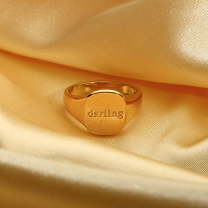 Detail van een 18k vergulde roestvrijstalen ring met darling gravure op zijden stof