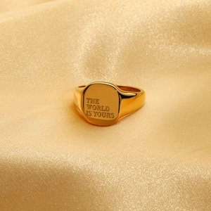 Detailopname van gouden zegelring met The World Is Yours gravure op satijn