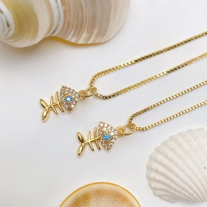 Macro view of gold fishbone pendants with zircon head and blue gemstone eye detail