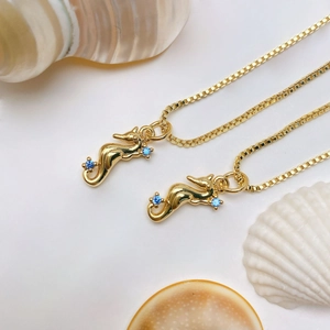 Detailed close-up of golden seahorse pendants with blue zircon on white shells