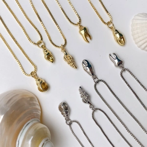 Detailed flat lay of nautical gold and silver ocean charm necklaces with shell pendants