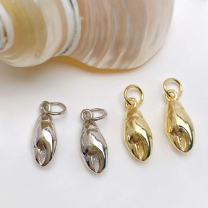 Detailed close-up of crab claw pendants in gold and silver finish with seashell background