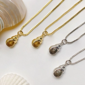 Macro shot of conch shell pendants in gold and silver finish with textured box chain details