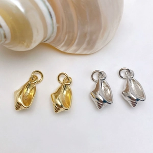 Close-up of gold and silver conch shell charms with spiral textures for jewelry making