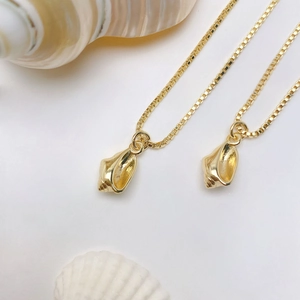 Close-up of golden sea shell pendants on box chains with natural conch decoration