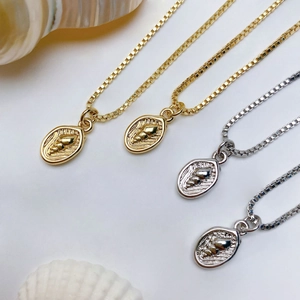 Macro shot of seashell relief pendants in gold and silver on classic box chains