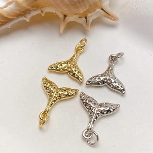 Detailed view of gold and silver whale tail pendants with textured surface for jewelry