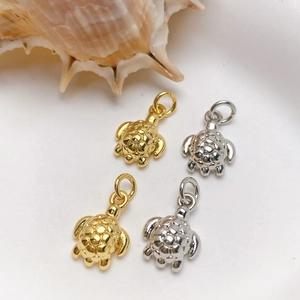 Macro detail of gold and silver sea turtle charms with fine checkered shell texture