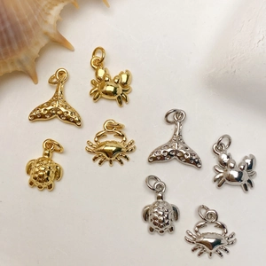 Detailed view of gold and silver plated sea life charms including whale tails and turtles