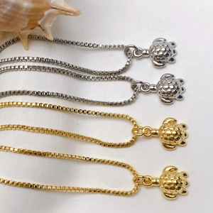 Detailed macro view of turtle pendants in gold and silver finish with box chains