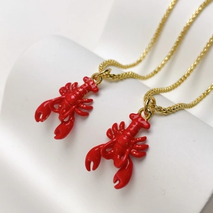 Detail of red lobster enamel pendant necklaces with gold finish on a white display