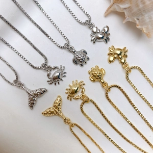 Detail of marine ocean pendants featuring crab turtle and whale tail in gold and silver