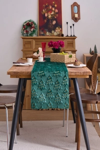 Close-up of green plush Christmas table runner with golden embroidery and tree patterns