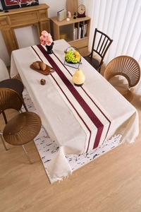 Detailed view of linen texture tablecloth with red striped runner and fringe trim