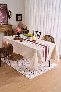 Close-up of minimalist beige linen tablecloth with red stripes and fringe tassels