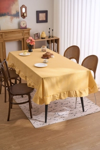 Détail de la nappe à carreaux jaunes avec des bords à volants dans une ambiance de salle à manger
