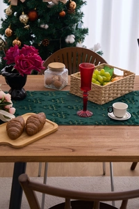 Detail of dark green plush Christmas table runner with golden tree embroidery patterns