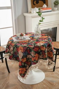 Detail of round jacquard tablecloth featuring vintage floral patterns and white cotton tassels