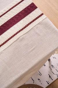 Detail of minimalist cotton linen tablecloth with red hollow knit patterns and fringe
