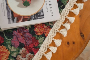 Detailed texture of jacquard floral tablecloth with elegant fringe trim on wood table