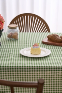 Détail de nappe à carreaux verts et blancs avec bordure à volants dans un décor de salle à manger