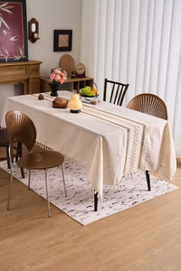 Detail of beige linen tablecloth with elegant openwork lace and handmade fringe tassels