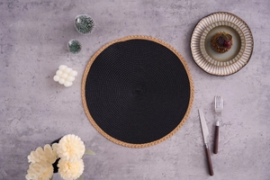 Detail of round woven placemat with black weave and light brown textured fringe trim
