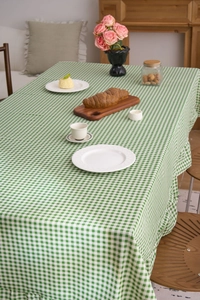 Détail d'une nappe à carreaux verts avec bordures à volants vintage et texture rustique