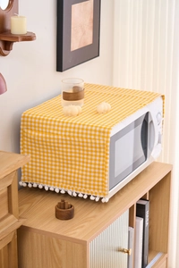 Macro detail of yellow gingham microwave dust cover with white pom-pom trim decoration