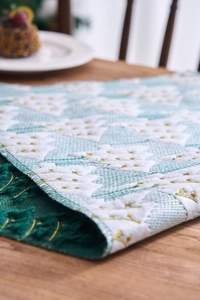 Detail of mint green Christmas table runner with white tree embroidery and green tassels