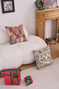 Detailed view of festive Christmas pillow covers with reindeer and berry patterns on a sofa