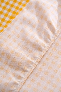 Détail du tissu en coton et lin à carreaux jaunes et blancs avec des coutures soignées