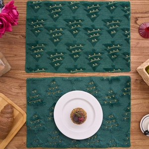 Close-up of green plush placemats with 3D embossed Christmas tree and gold embroidery