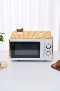 Detail showing yellow plaid refrigerator dust cover with white pom-pom fringe edges