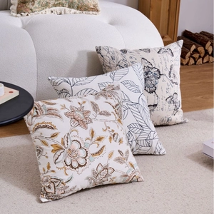Modern geometric pillow covers with botanical patterns on a minimalist cream sofa