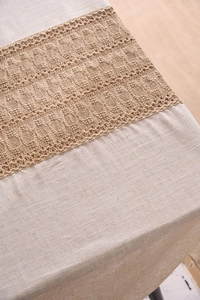Close-up of rustic linen tablecloth with brown hollow crochet lace stitching and texture