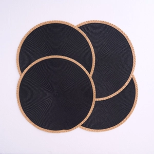 Detail of round black woven placemats with brown tassel border in a set of four pieces