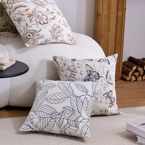 Three decorative pillows with floral, butterfly, and leaf patterns on a white sofa