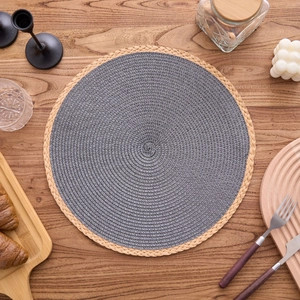 Detail of round woven placemat with gray center and wood-colored border on a wooden table