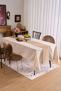 Detailed close-up of beige linen tablecloth with tassels and bohemian hollow table runner